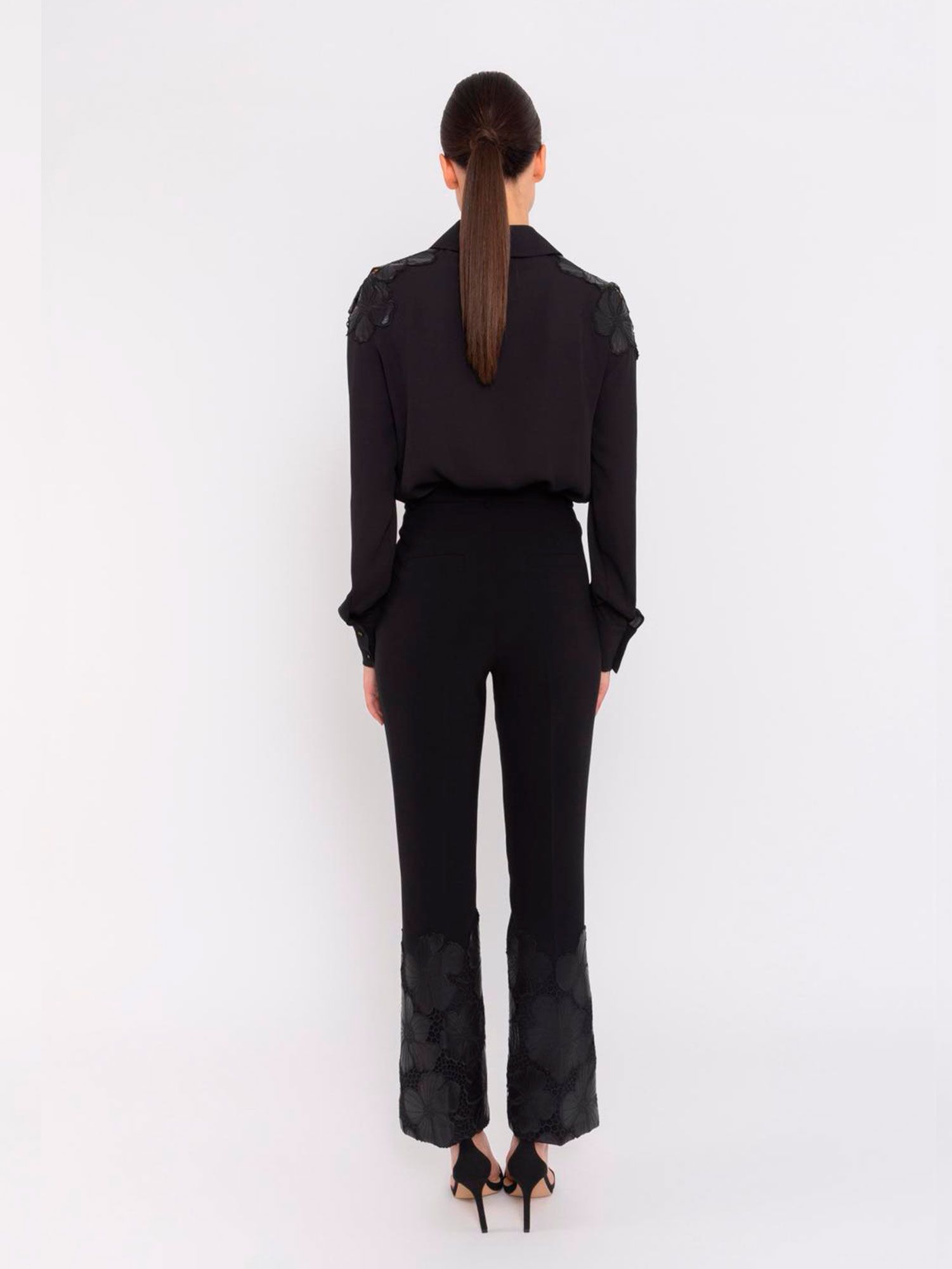 Conjunto negro sofisticado con bordados florales en polipiel en hombros y bajo del pantalón. Diseño elegante y femenino, ideal para eventos o cenas especiales.